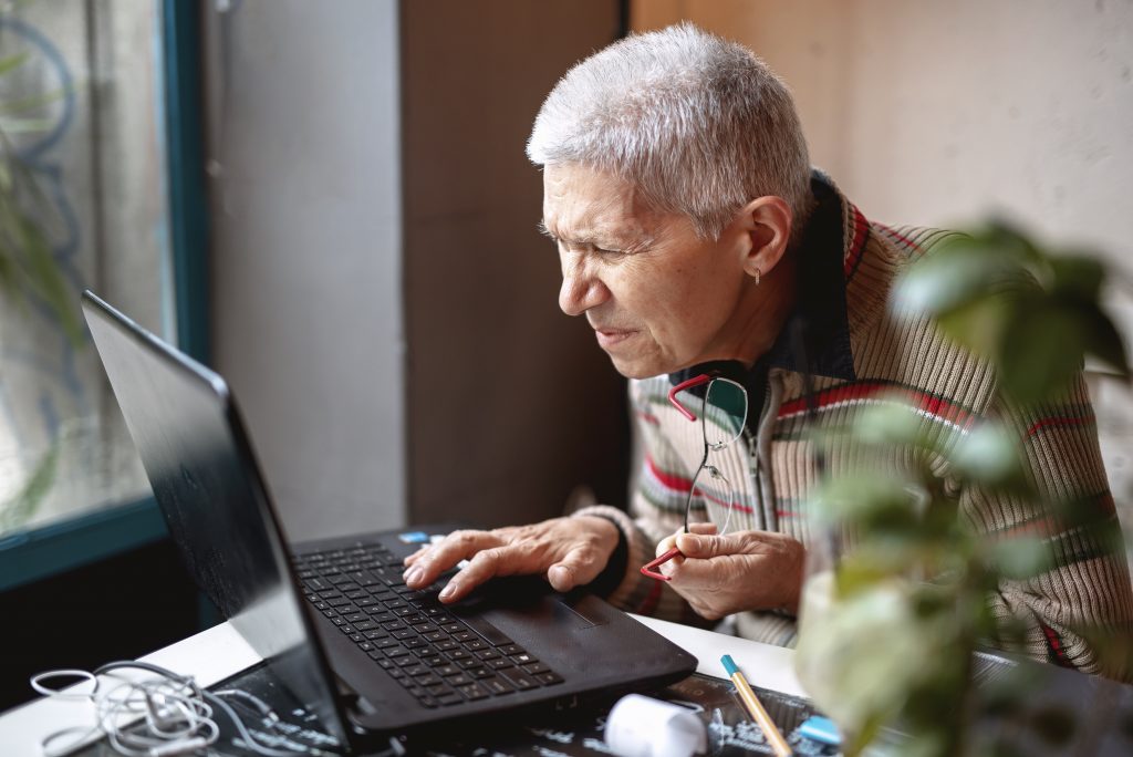 Ältere Frau sitzt am Computer und liest